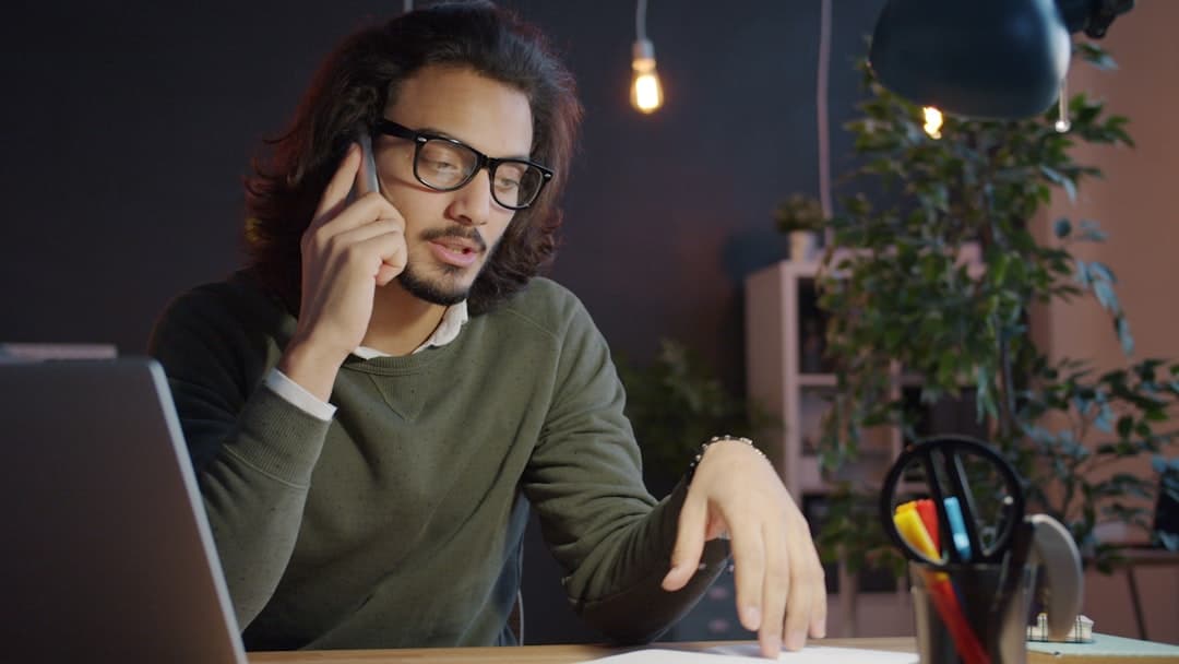 Homeowner on the phone negotiating with their mortgage lender at a desk with documents